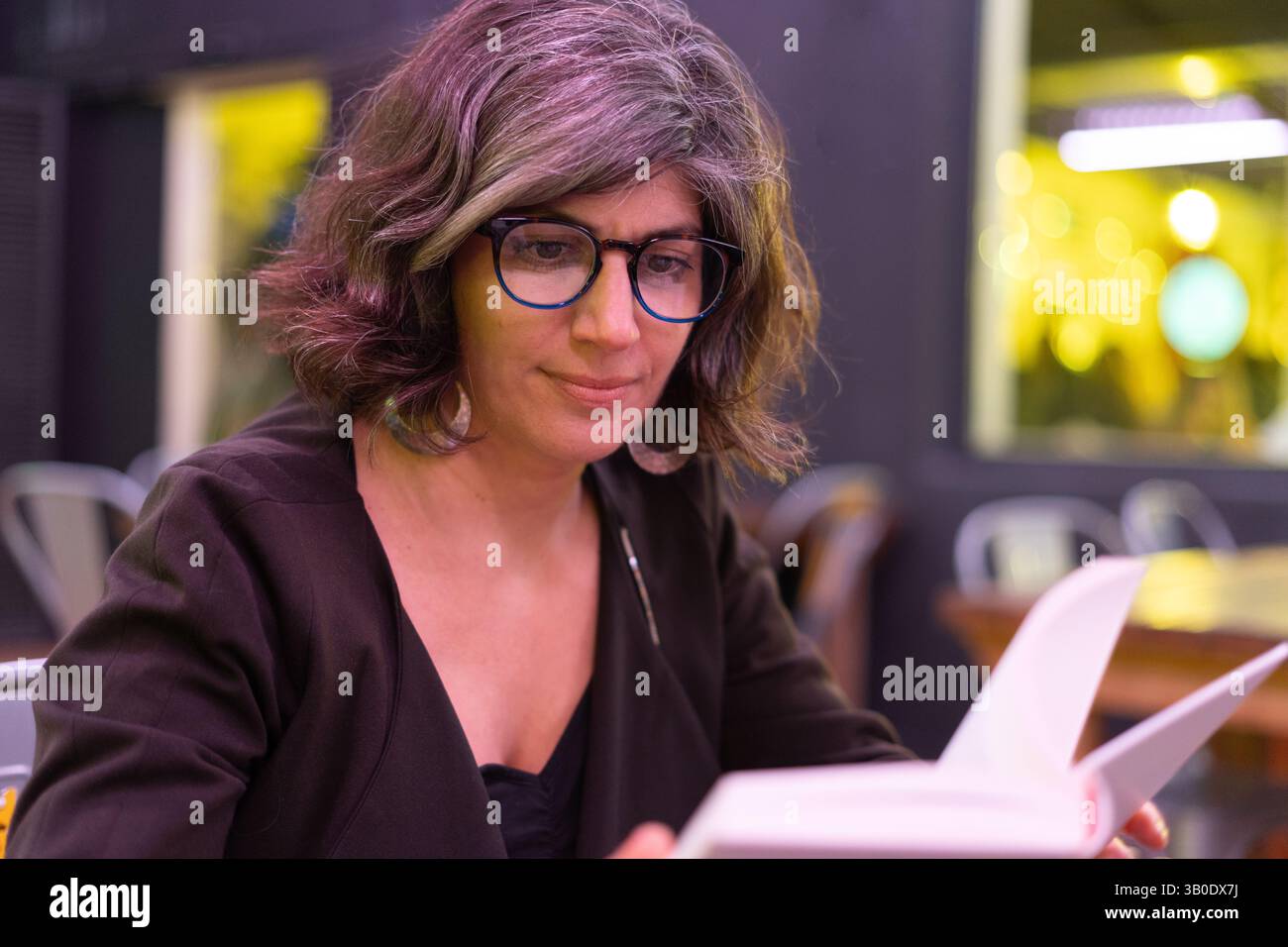 Donna d'affari che legge un libro in un ristorante Foto Stock