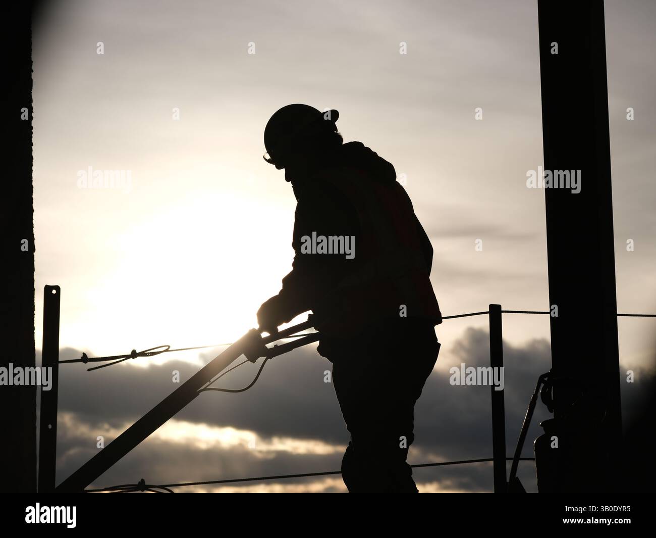 Incorniciato dalla luce crescente: Una silhouette da costruzione al lavoro Foto Stock