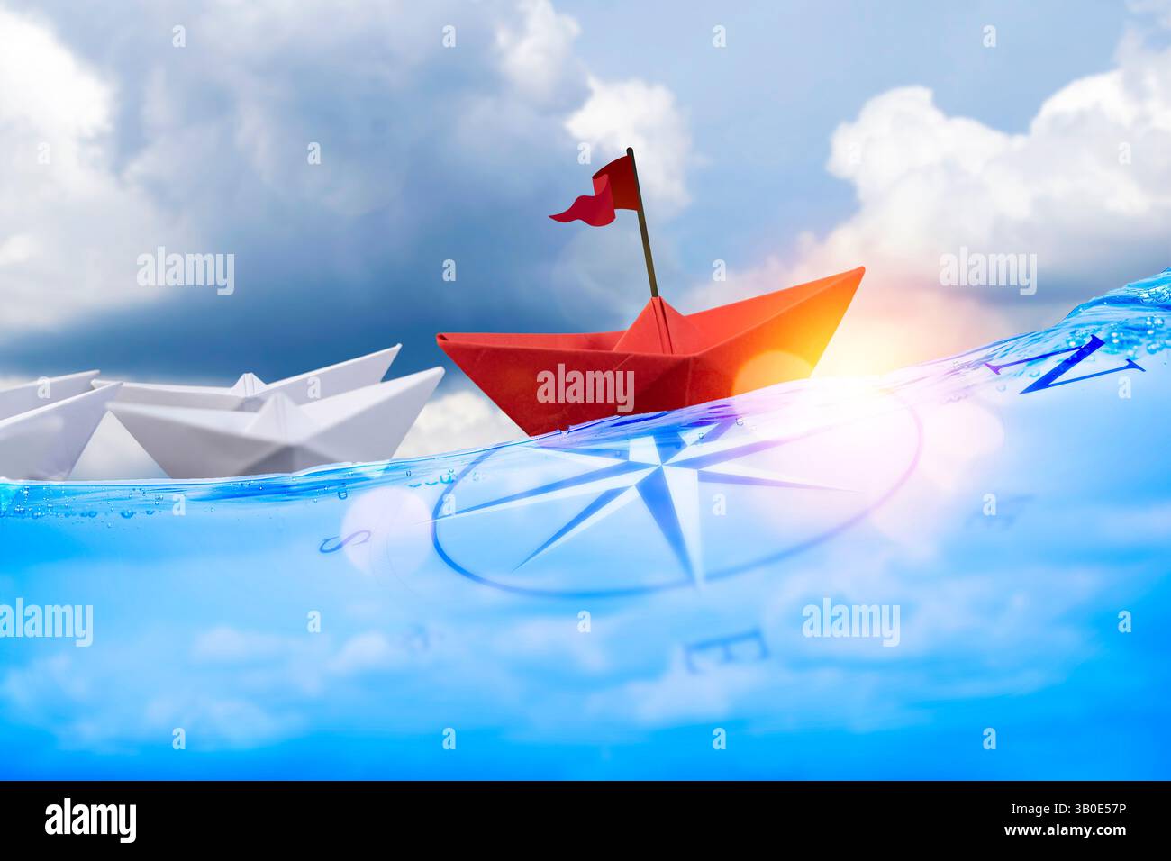 Red Paper Boat on Compass a capo Di Una flotta di piccole imbarcazioni bianche. Concetto di leadership aziendale. Una barca rossa e un gruppo di barche bianche su un backgroun blu Foto Stock