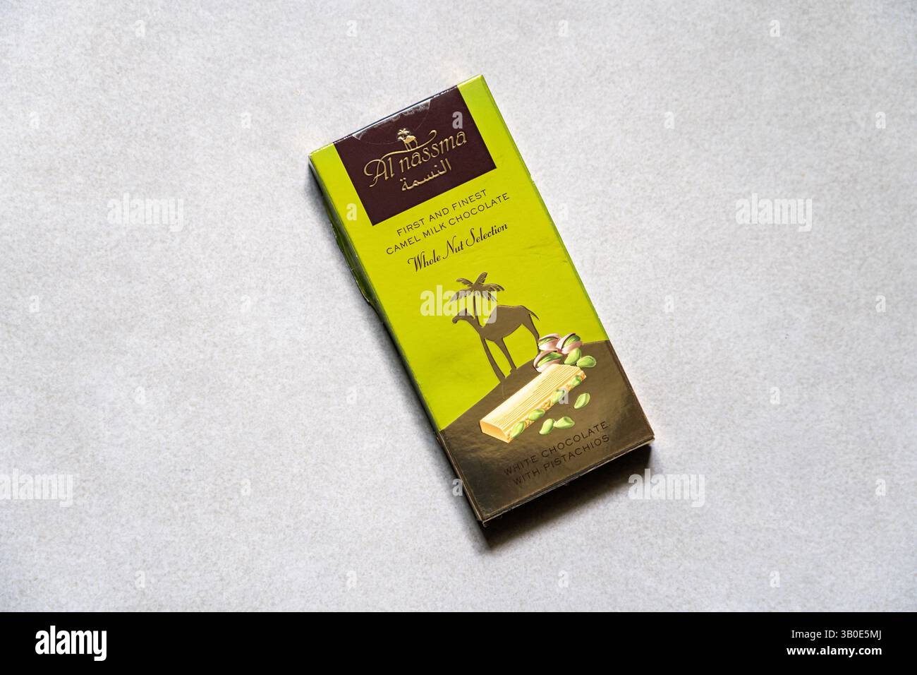 Un bar di cioccolato bianco al Nassma con cioccolato al latte di cammello di pistacchi su sfondo grigio piastrelle. Foto Stock