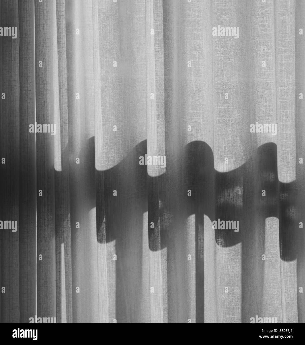 foto in bianco e nero della tenda della finestra in una camera d'albergo con luce che splende creando un'ombra ondulata attraverso il movimento verticale del materiale della tenda Foto Stock foto in bianco e nero della tenda della finestra in una camera d'albergo con luce che splende creando un'ombra ondulata attraverso il movimento verticale del materiale della tenda Foto Stock