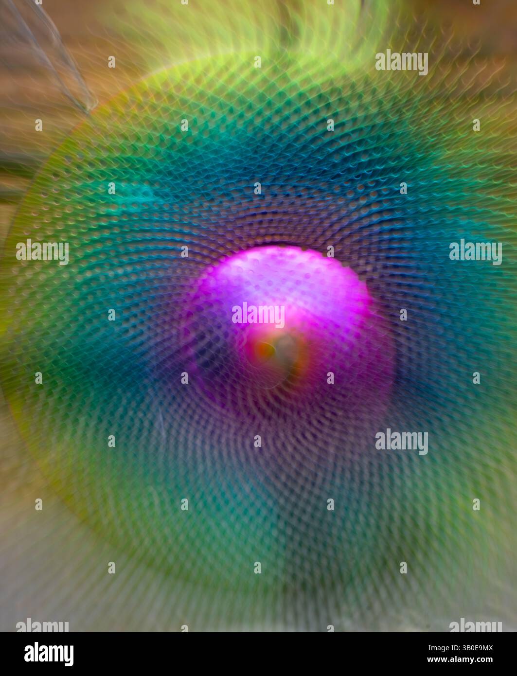 sfocatura astratta della sfera in metallo viola verde e gialla con fori ingranditi con esposizione prolungata e zoom intenzionale dell'obiettivo per creare movimento Foto Stock