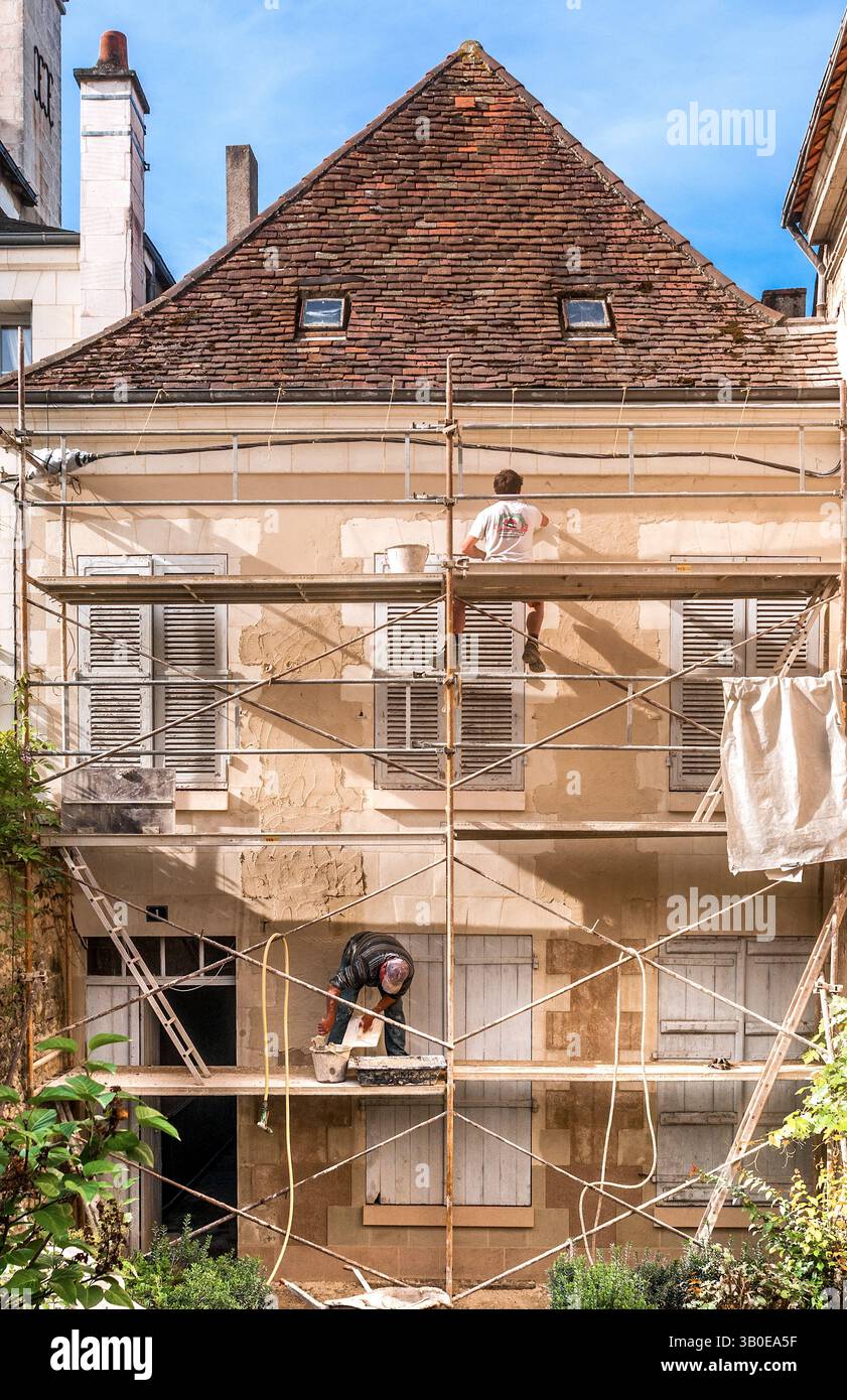 Appaltatori edili su impalcature che applicano intonaco di finitura alla parete di una casa 18C in fase di ristrutturazione - Preuilly-sur-Claise, Indre-et-Loire (37), Francia Foto Stock