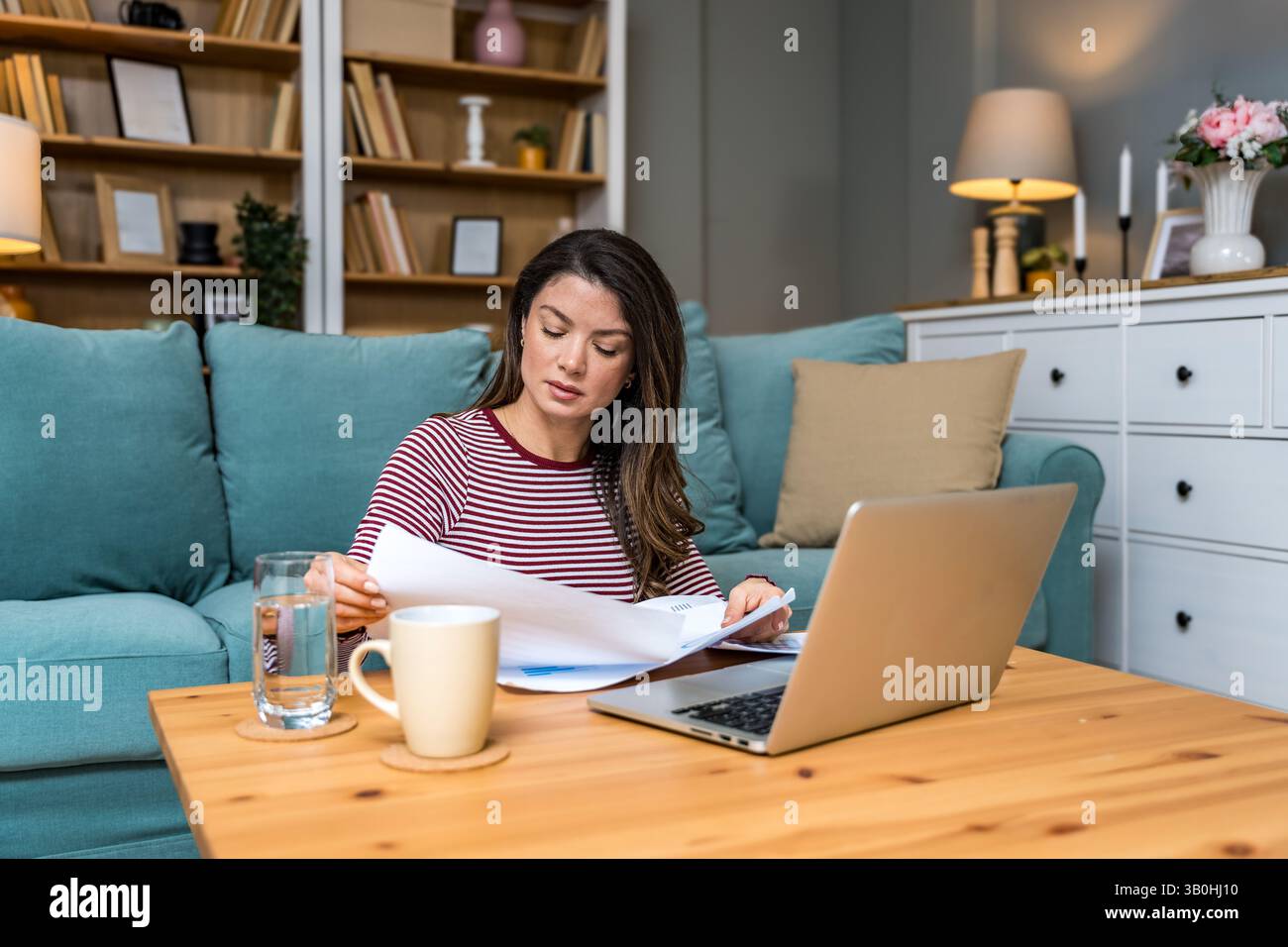 Crisi finanziaria. Giovane donna d'affari preoccupata, seduta a casa, che cerca di trovare una via d'uscita, calcolando le entrate e le spese della sua piccola dimensione globale Foto Stock