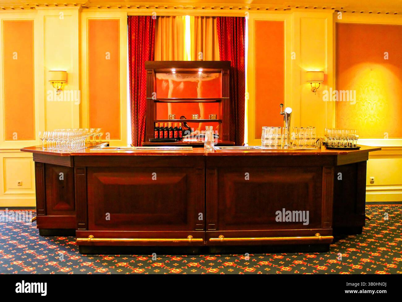 Elegante bar dell'hotel con bancone in legno, vetri e illuminazione calda. Foto Stock
