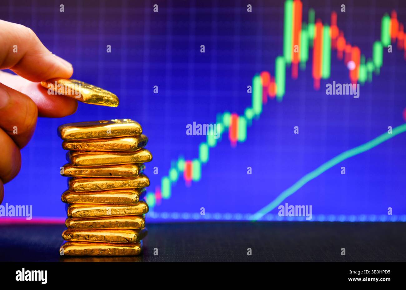 Primo piano con la mano che tiene una mano dorata fissa il grafico a candelabro. Contesto , concetto di fluttuazioni dei prezzi dell' oro. Foto Stock