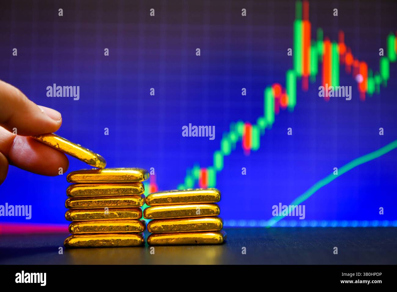 Primo piano con la mano che tiene una mano dorata fissa il grafico a candelabro. Contesto , concetto di fluttuazioni dei prezzi dell' oro. Foto Stock