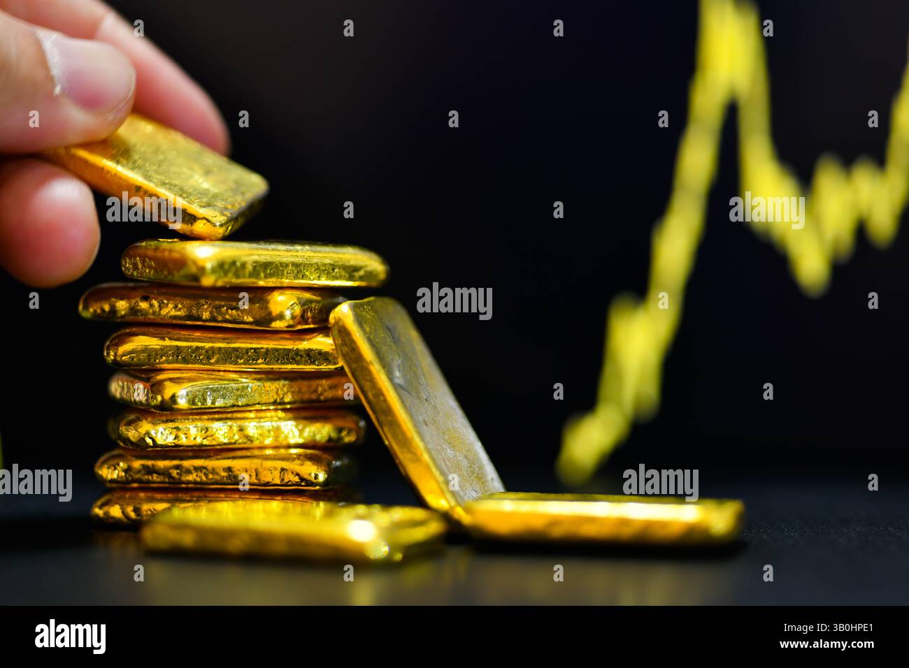 Primo piano con la mano che tiene una mano dorata fissa il grafico a candelabro. Contesto , concetto di fluttuazioni dei prezzi dell' oro. Foto Stock