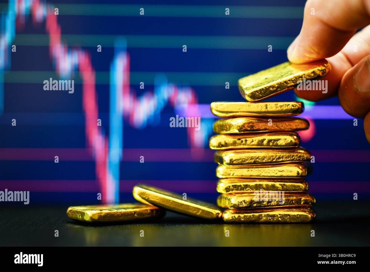Primo piano con la mano che tiene una mano dorata fissa il grafico a candelabro. Contesto , concetto di fluttuazioni dei prezzi dell' oro. Foto Stock