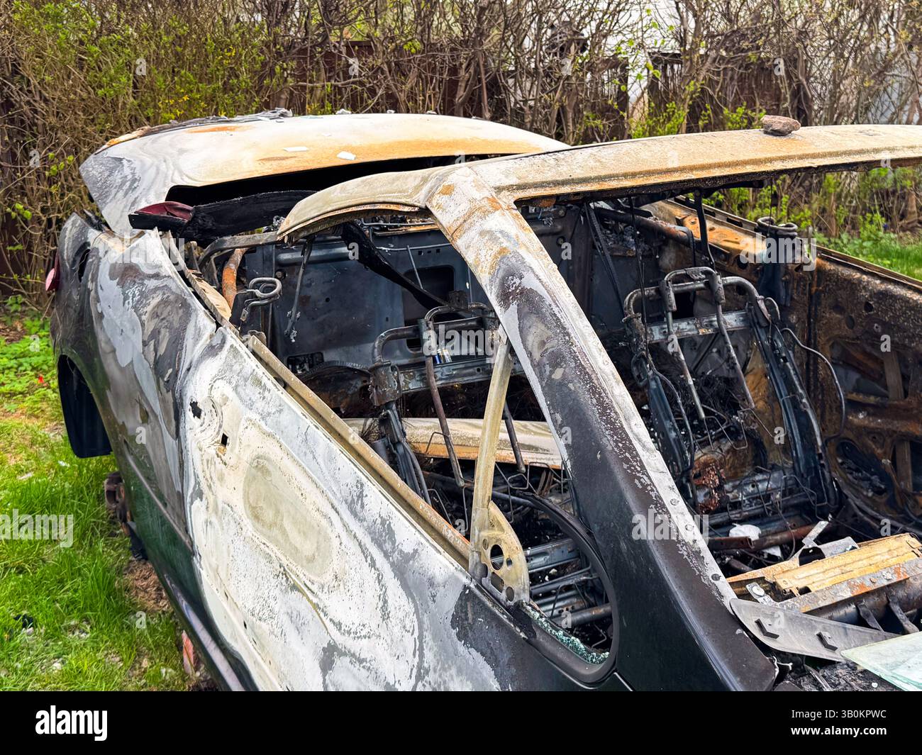 Tetto dell'auto e telaio dell'abitacolo bruciati che mostrano metallo deformato dal calore, finestrini mancanti e strutture dei sedili esposte dopo la completa distruzione della parte superiore della b Foto Stock