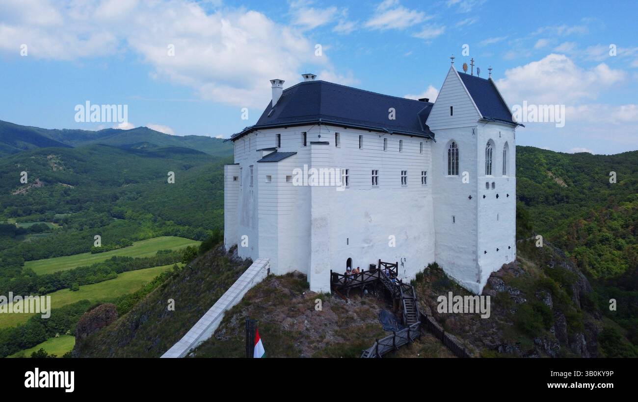 Il castello medievale ungherese si erge sulla cima della montagna. Panorama panoramico e vista panoramica. Foreste e valli verdeggianti, fortezza storica. Foto Stock