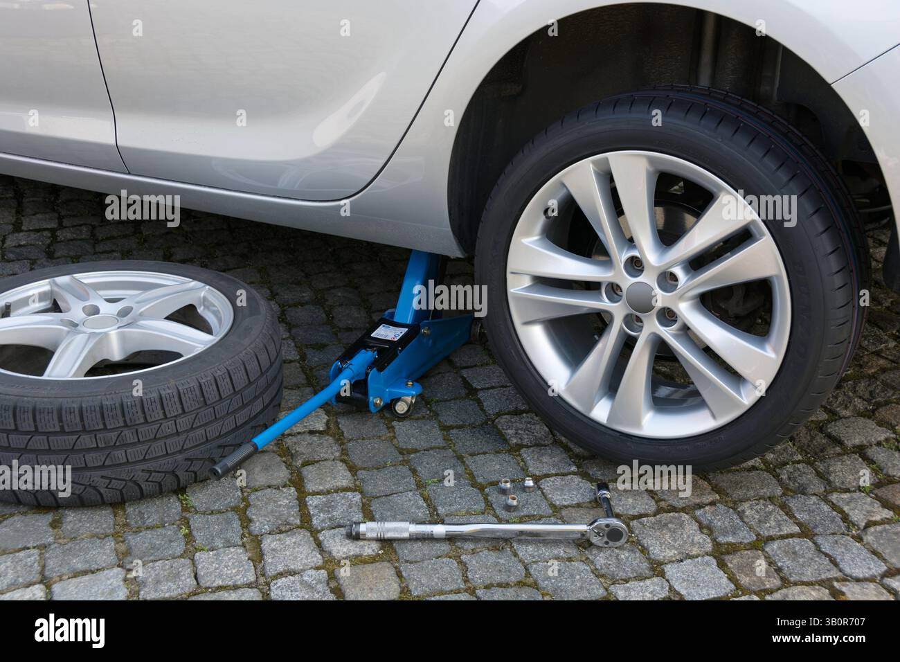 Cambiare le ruote con un martinetto su un'auto moderna Foto Stock
