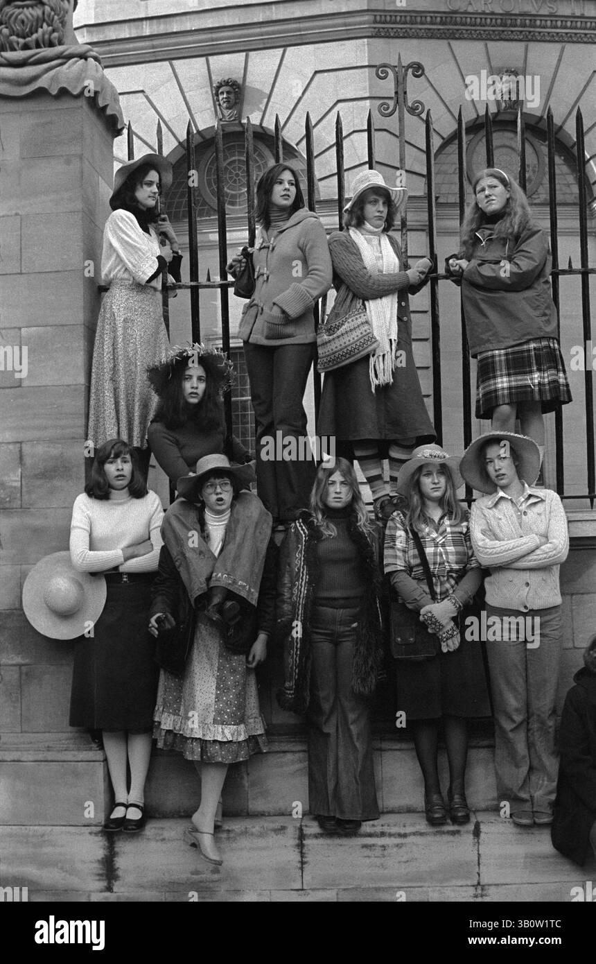 Studentesse universitarie britanniche degli anni '1970. La mattina del primo maggio, sono stati svegli tutta la notte per vedere l'alba il primo giorno di primavera, come è tradizione annuale. Studentesse dell'Università di Oxford che guardano le celebrazioni - morris che ballano e ballano per strada dalla ringhiera fuori dallo Sheldonian Theatre. Indossati in modo elegante e accogliente, per lo più sportivi cappelli di paglia estivi. Oxfordshire, Inghilterra 1976 HOMER SYKES Foto Stock