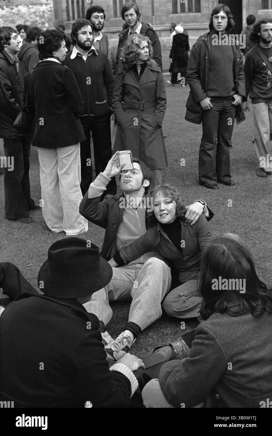 Mattina di maggio, Oxford 1976. Un gruppo di studenti seduti a divertirsi godendosi le tradizionali celebrazioni mattutine del primo maggio, terminando una bottiglia di qualcosa di forte. Bevendo da una bottiglia tra amici con il braccio intorno alla sua ragazza. Anni '1970 Regno Unito. Oxfordshire, Inghilterra, HOMER SYKES Foto Stock
