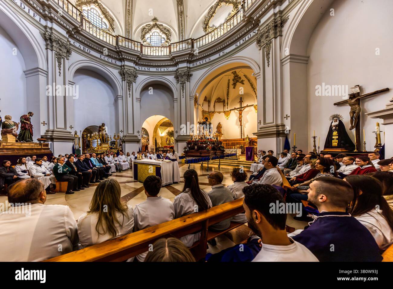 Nella Iglesia San Pedro, numerosi membri dell'Hermandad del Bautismo de Nuestro Señor Jesucristo prendono parte a una cerimonia religiosa. Una persona legge da un libro mentre gli altri ascoltano. Calle Trabuco, Cuenca, Castilla-la Mancha, Spagna Foto Stock