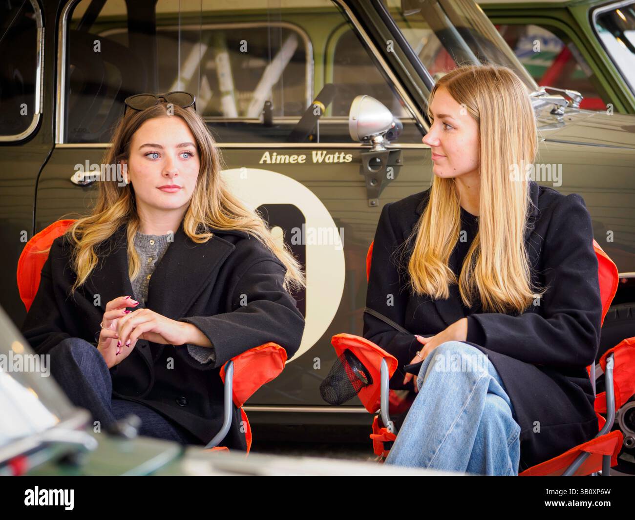 Due donne attraenti sedute nel paddock al 82 Members Meeting, Goodwood Motor Circuit, West Sussex UK Foto Stock
