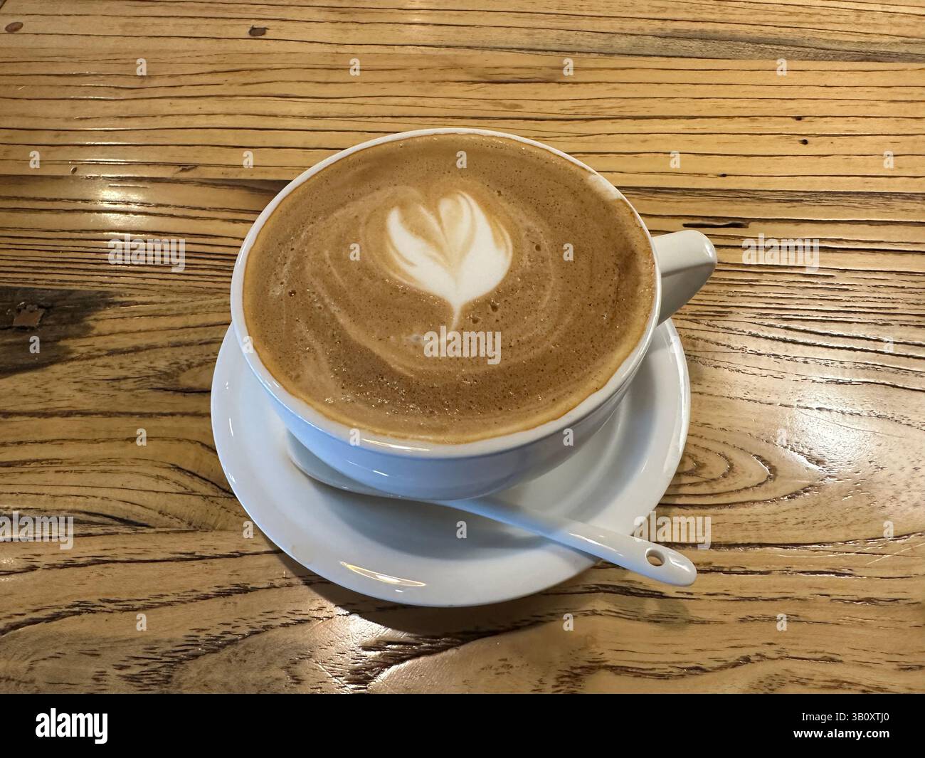 Un latte splendidamente artigianale, completo di un design a cuore, pronto per essere gustato al bar. - Immagine stock catturata con smartphone