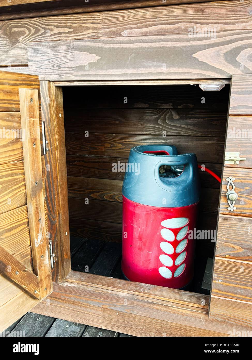 Armadio in legno che ospita una bombola di gas rossa vivace per pratiche soluzioni di immagazzinamento dell'energia Foto Stock