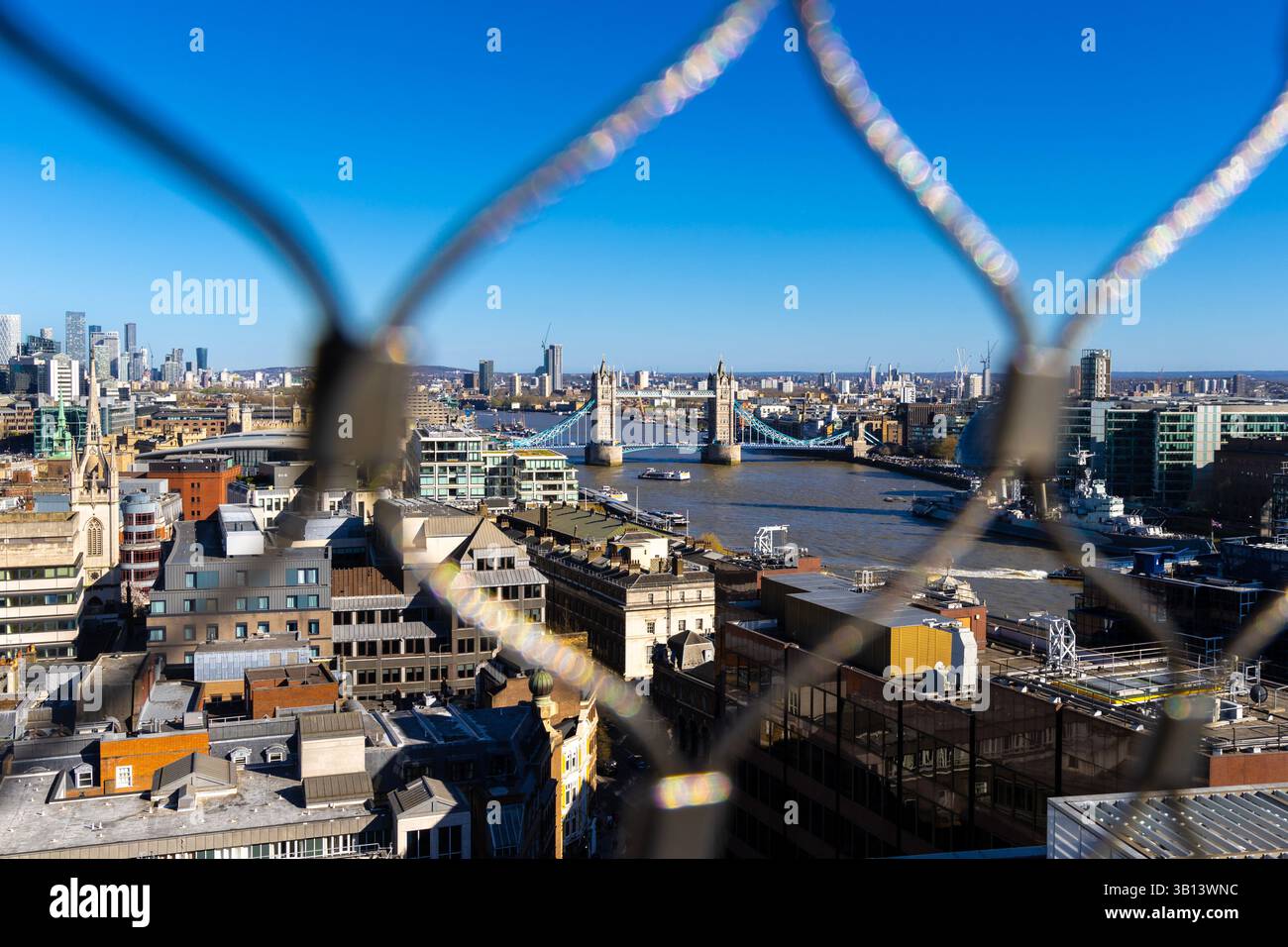Vista del Tower Bridge attraverso una recinzione in cima al Monumento al grande incendio di Londra, Inghilterra Foto Stock