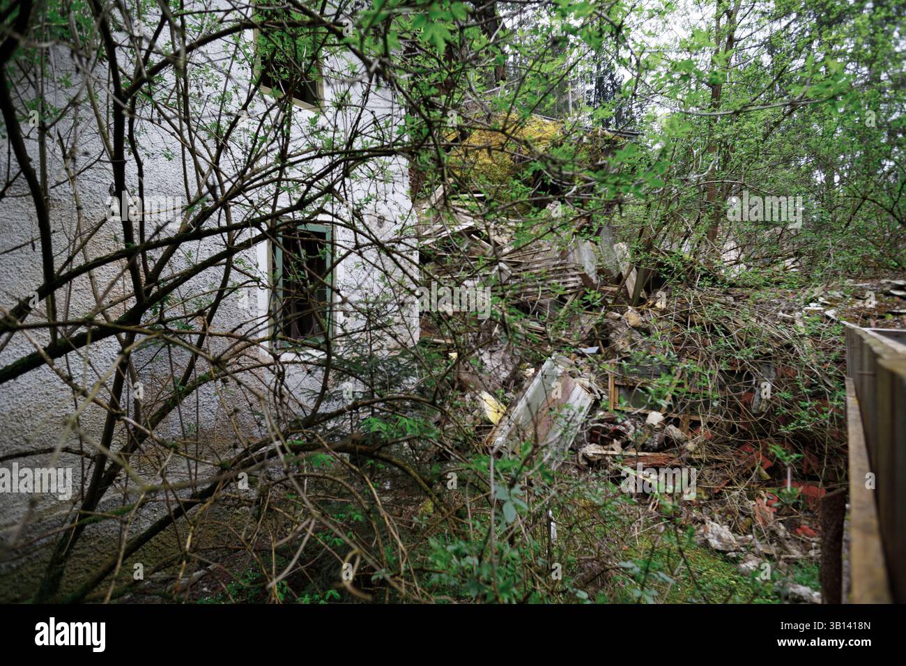 Bad Illstern, italia, posto perso. L'immagine mostra il lato di un edificio fatiscente con finestra, parzialmente oscurata dagli alberi, con un mucchio di detriti accanto ad esso Foto Stock Bad Illstern, italia, posto perso. L'immagine mostra il lato di un edificio fatiscente con finestra, parzialmente oscurata dagli alberi, con un mucchio di detriti accanto ad esso Foto Stock