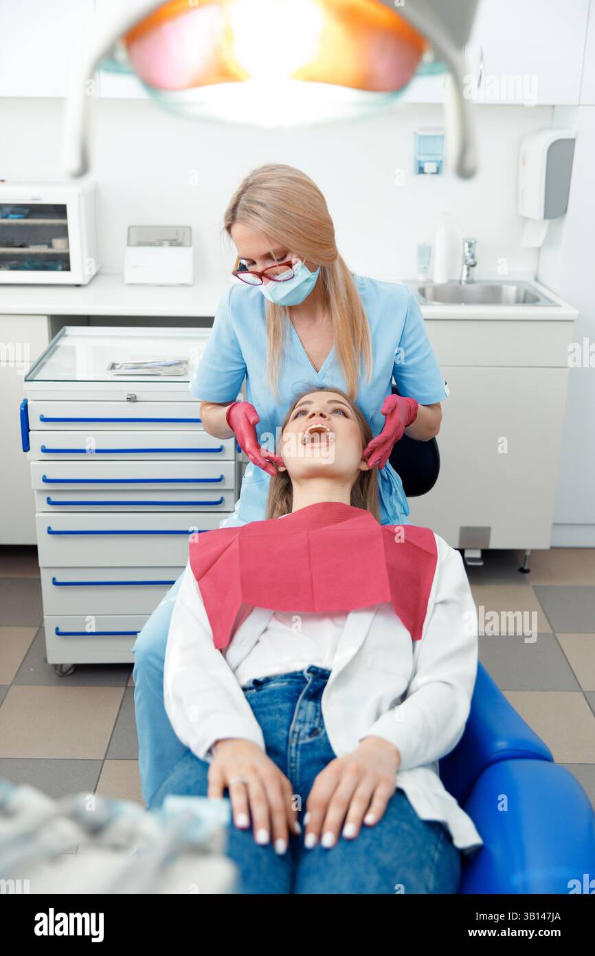 sbiancamento dei denti, dentista che controlla i denti, esame dentale, denti del paziente, ufficio ospedaliero, garantire la salute dentale Foto Stock
