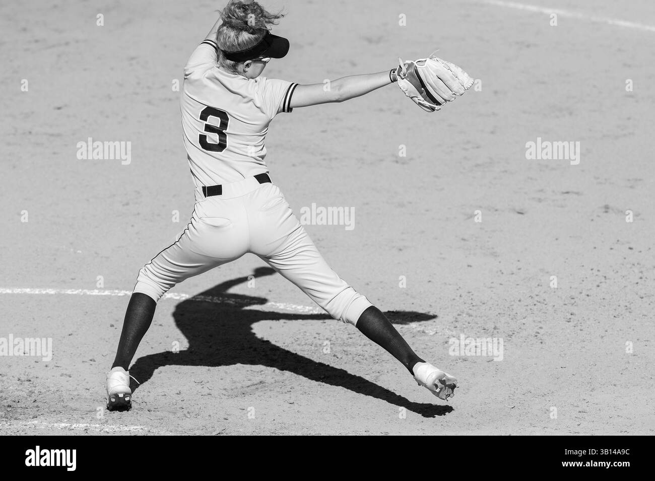 Un lanciatore Softball a passo veloce è in modalità di atterraggio completo in bianco e nero Foto Stock