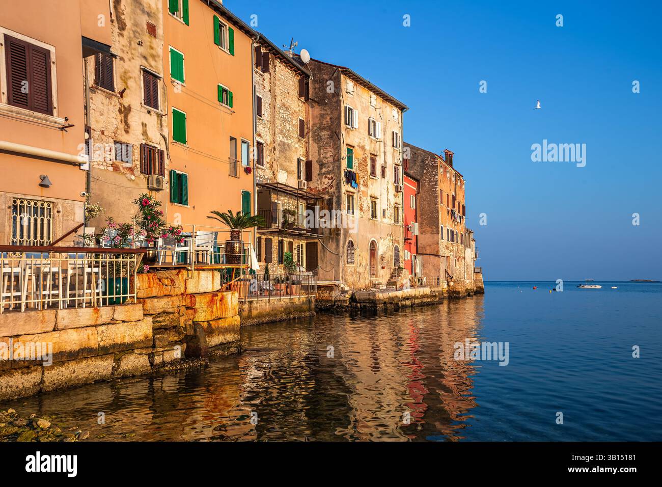 Rovigno, Croazia - case tradizionali nella città vecchia di Rovigno in un caldo pomeriggio estivo con colori caldi e vivaci e un cielo azzurro limpido al tramonto presso la A. Foto Stock