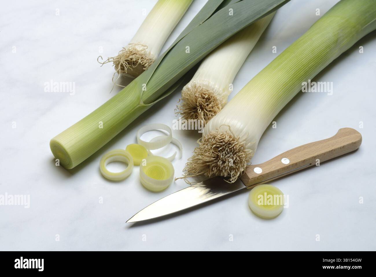 Porri, bastoncini di porri e anelli di porro con un coltello Foto Stock