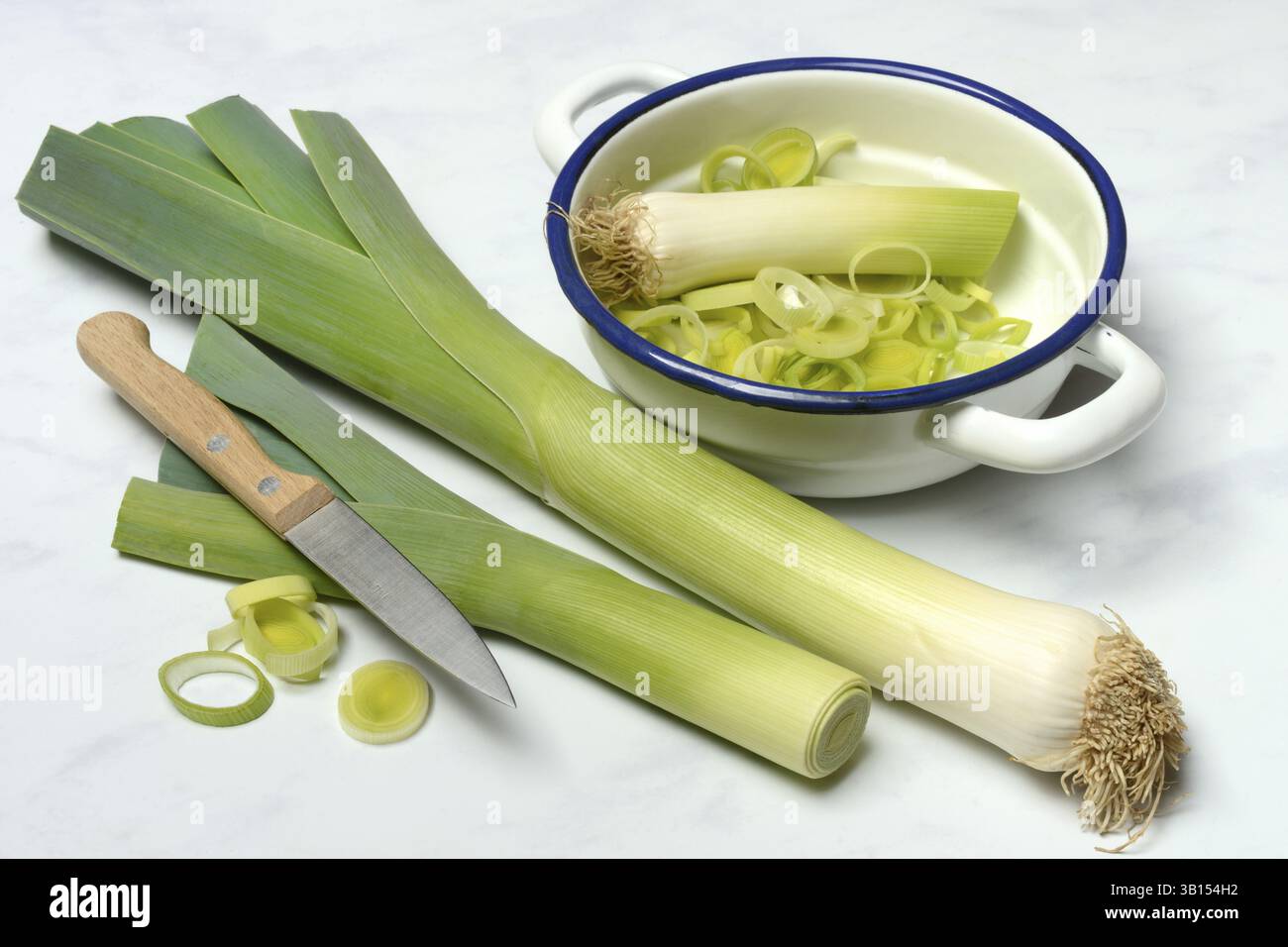 Porri, bastoncini di porro e anelli di porro in un recipiente Foto Stock