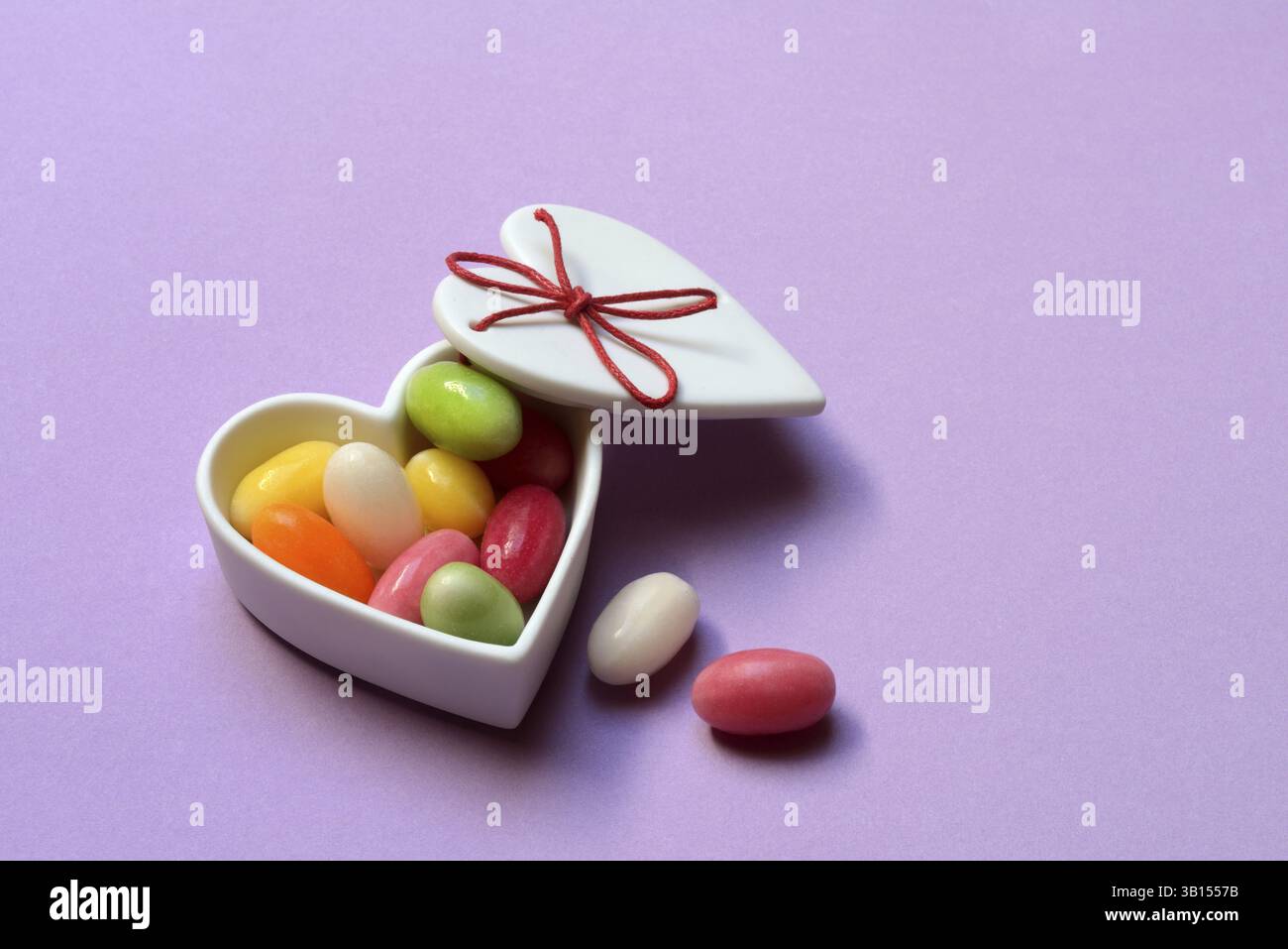 Uova di zucchero colorate in un recipiente di ceramica a forma di cuore, uova di Pasqua, uova di Pasqua a forma di zucchero Foto Stock