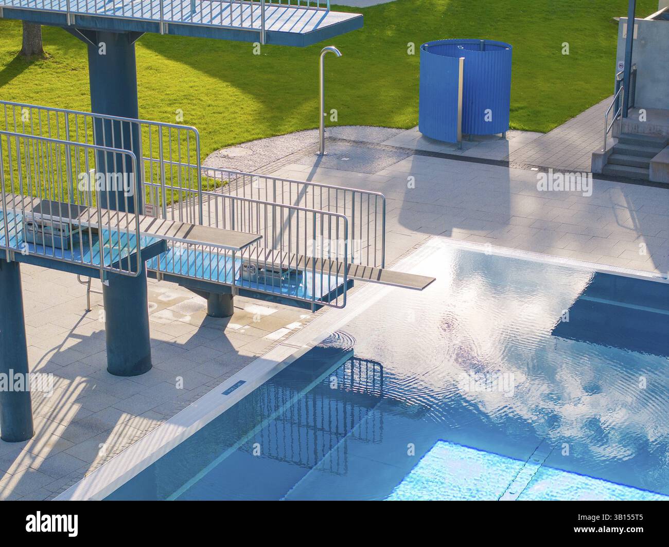 Parte di una piscina all'aperto con trampolino e riflessi d'acqua, adiacente a un'area verde, piscina all'aperto Calw Stammheim, Calw, Foresta Nera, Germania, E. Foto Stock