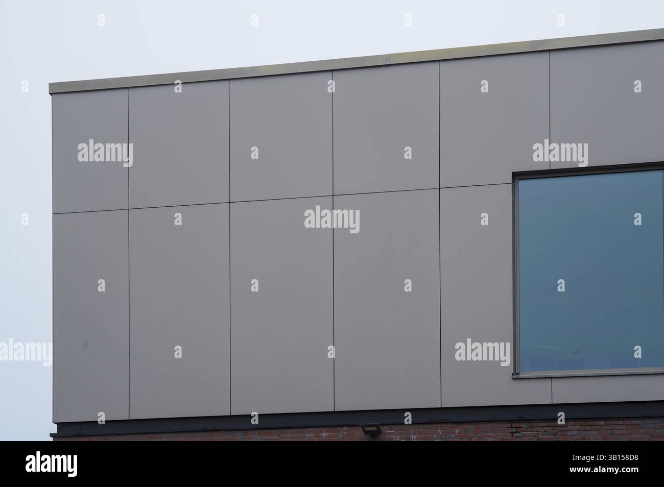 Borken, NRW, Germania, facciata in pannelli grigi di un edificio moderno con una finestra blu che riflette il cielo, che mostra un design architettonico contemporaneo, UE Foto Stock