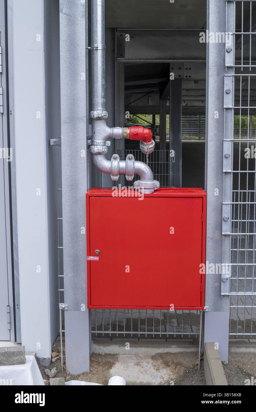 Collegamento e armadio per idranti antincendio rossi per garantire la sicurezza degli edifici con tubi galvanizzati e recinzione a griglia metallica, Borken, NRW, Germania, Europa Foto Stock