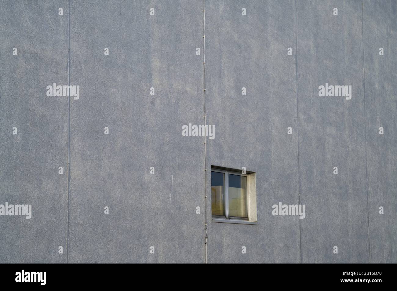Piccola finestra che interrompe la grande facciata in cemento grigio dell'edificio industriale, Borken, NRW, Germania, Europa Foto Stock