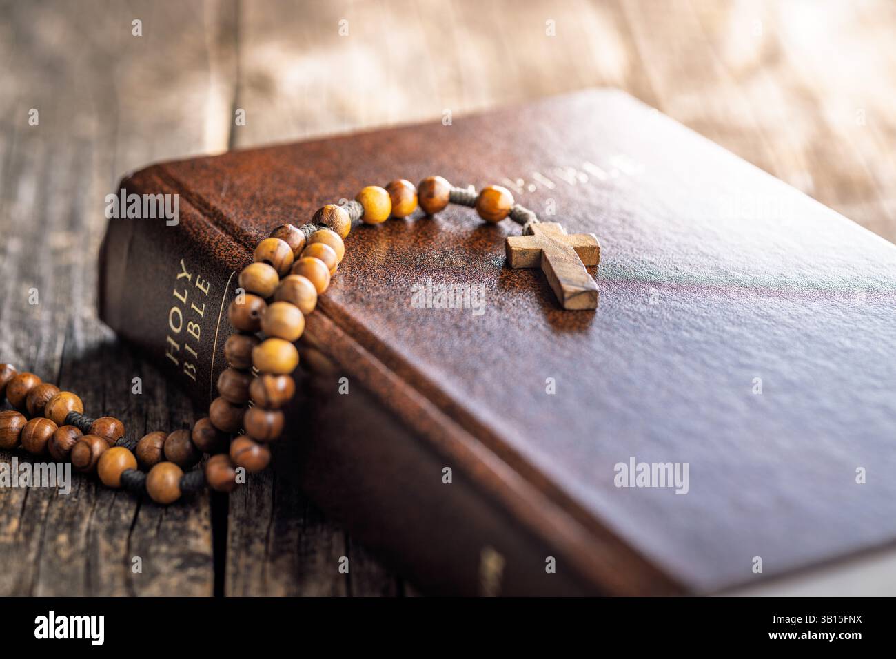 Perline di rosario in legno e Sacra Bibbia su un tavolo di legno. Foto Stock