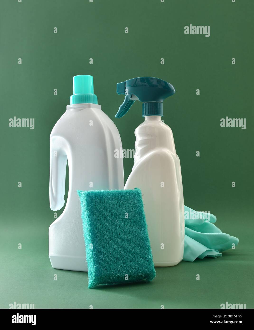 Dettaglio della fornitura di prodotti per la pulizia del bagno con strumenti quali flacone disinfettante, guanti in gomma e spugnetta isolata su sfondo verde. F Foto Stock