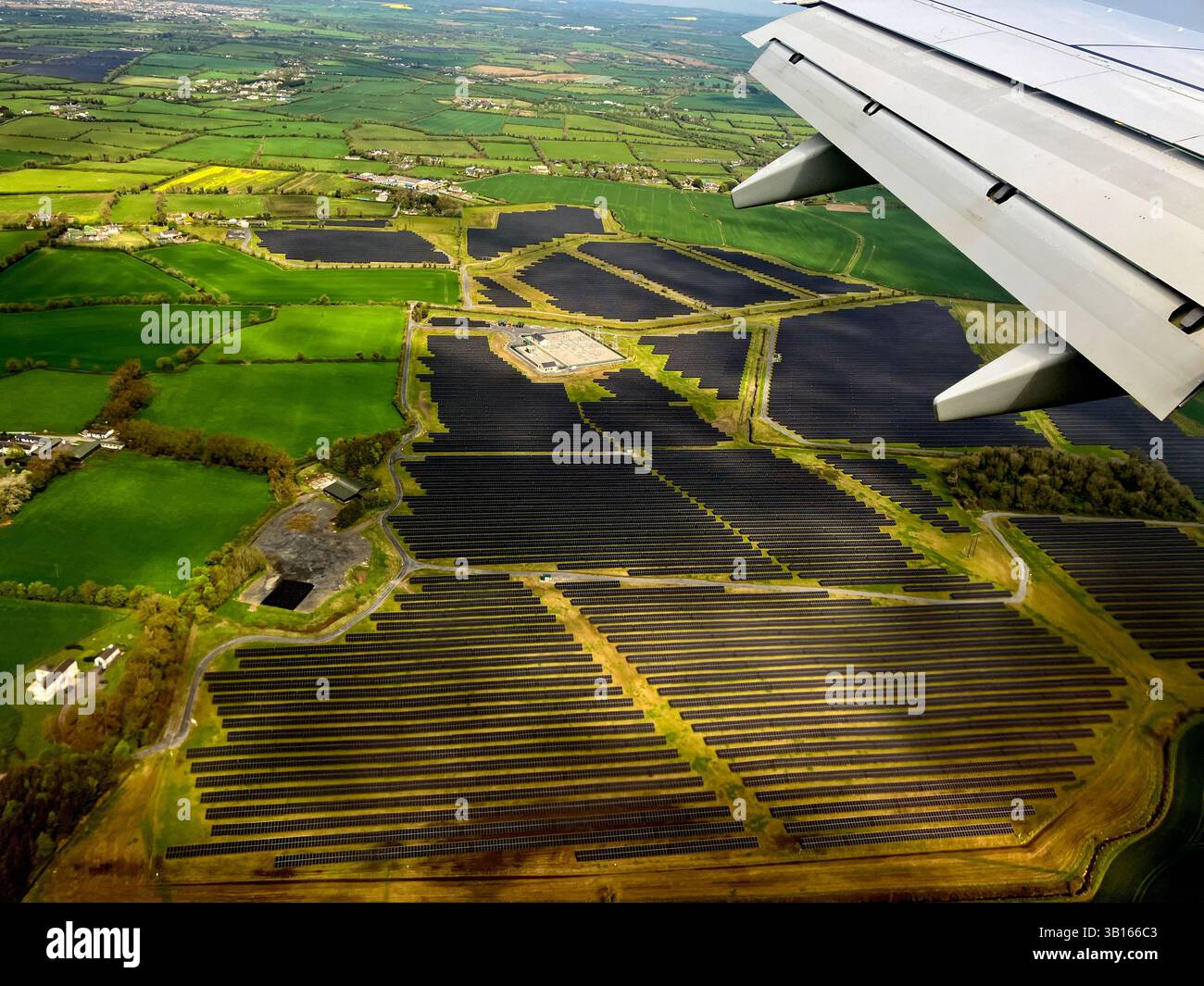 Pannelli a energia solare nel campo vicino all'aeroporto di Dublino visti dalla finestra dell'aereo di atterraggio. Foto Stock