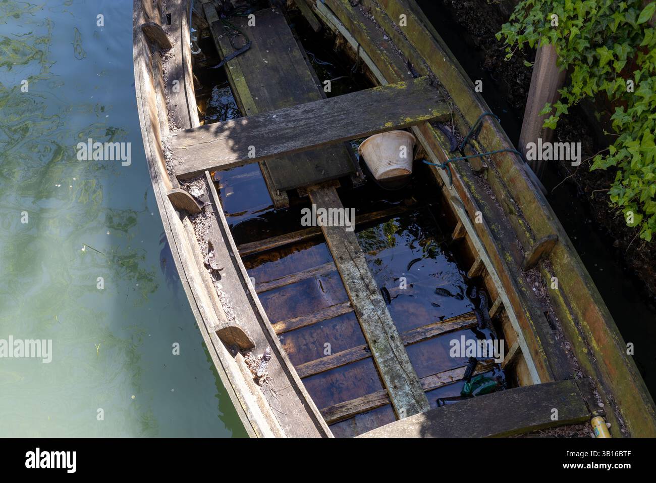 Barca in legno abbandonata sommersa nel canale veneziano Foto Stock