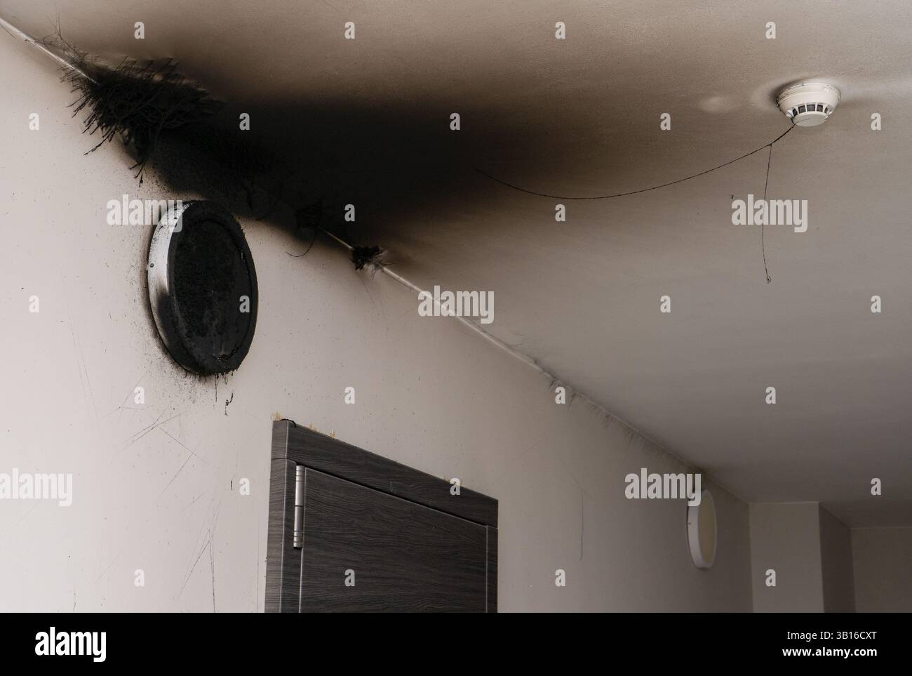 Lampada LED bruciata. Una lampada a paralume sulla parete dopo un incendio. Combustione spontanea e incendio in un edificio residenziale. Sensore di allarme antincendio interno. Fumo nero Foto Stock