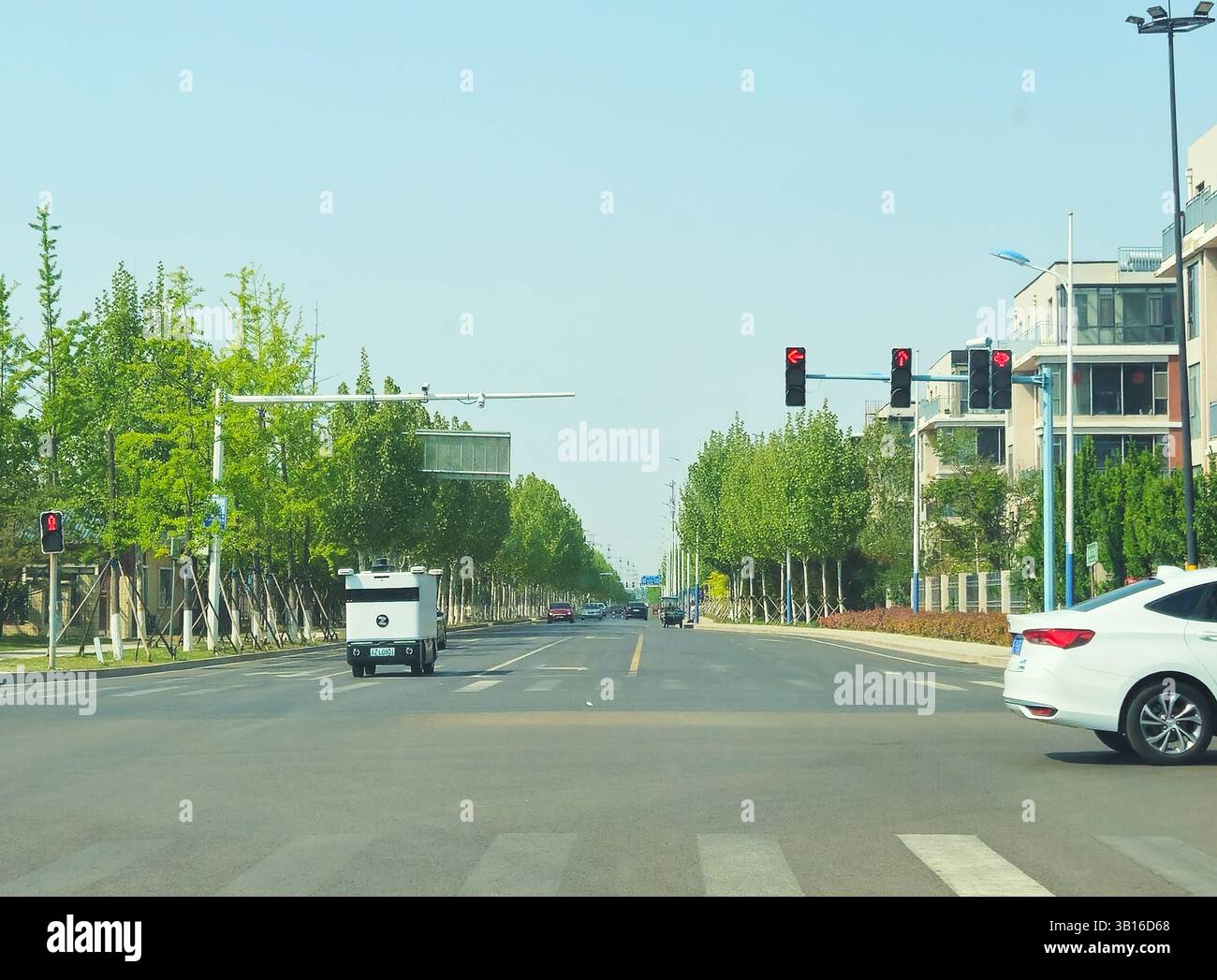 Veicolo per la consegna autonoma che si ferma al semaforo nell'ambiente urbano cinese moderno, Shandong, Cina Foto Stock