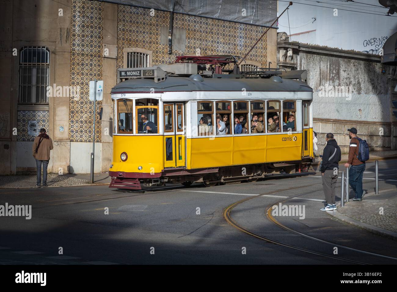 Lisbona, Portogallo. 26 febbraio 2025. Tram giallo sulla strada di Lisbona, Portogallo. Casa di sfondo con piastrelle. Foto Stock