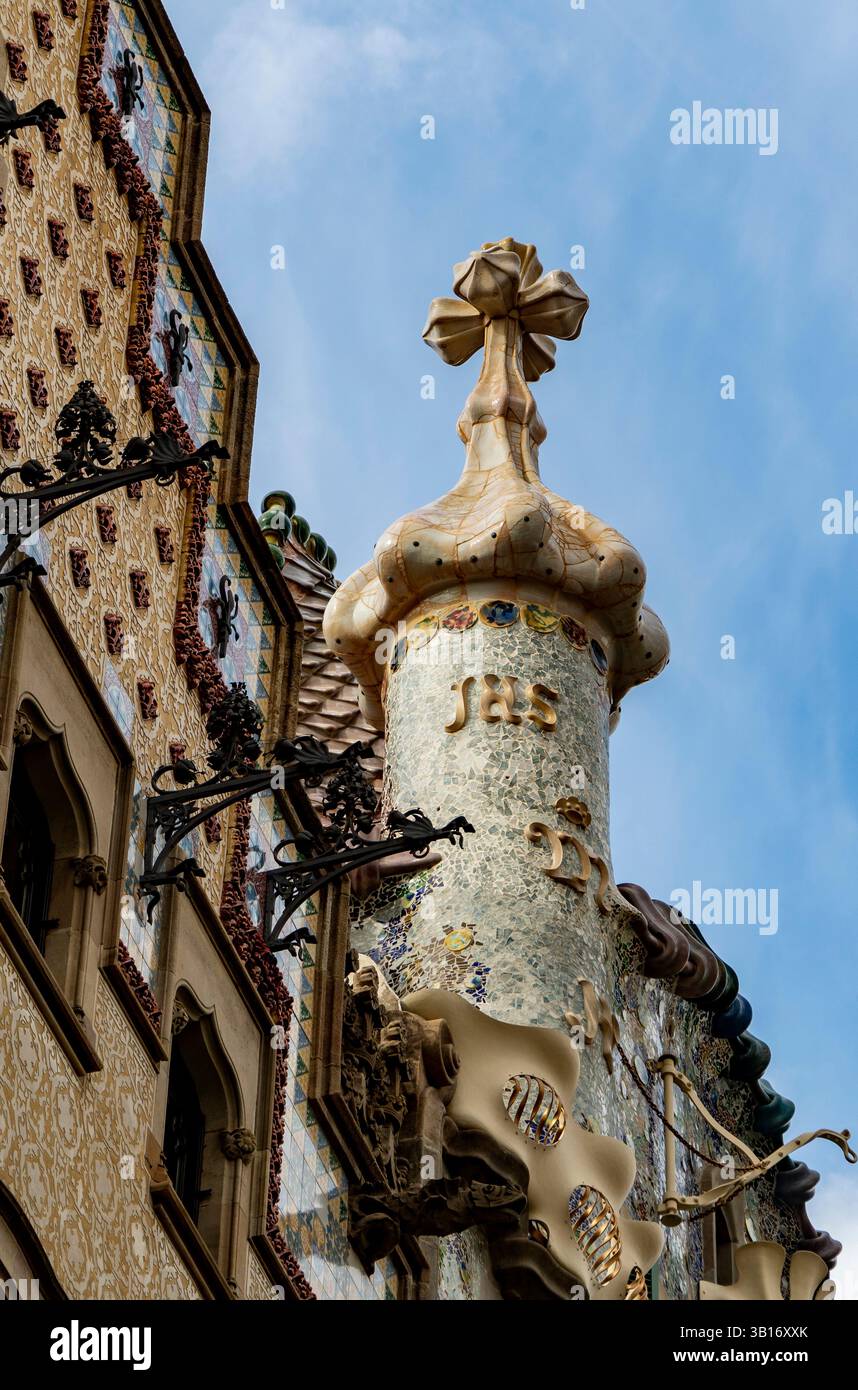 Una vista ravvicinata di un elemento architettonico decorativo caratterizzato da una guglia unica con una croce in cima, adornata con piastrelle colorate e intricate desi Foto Stock