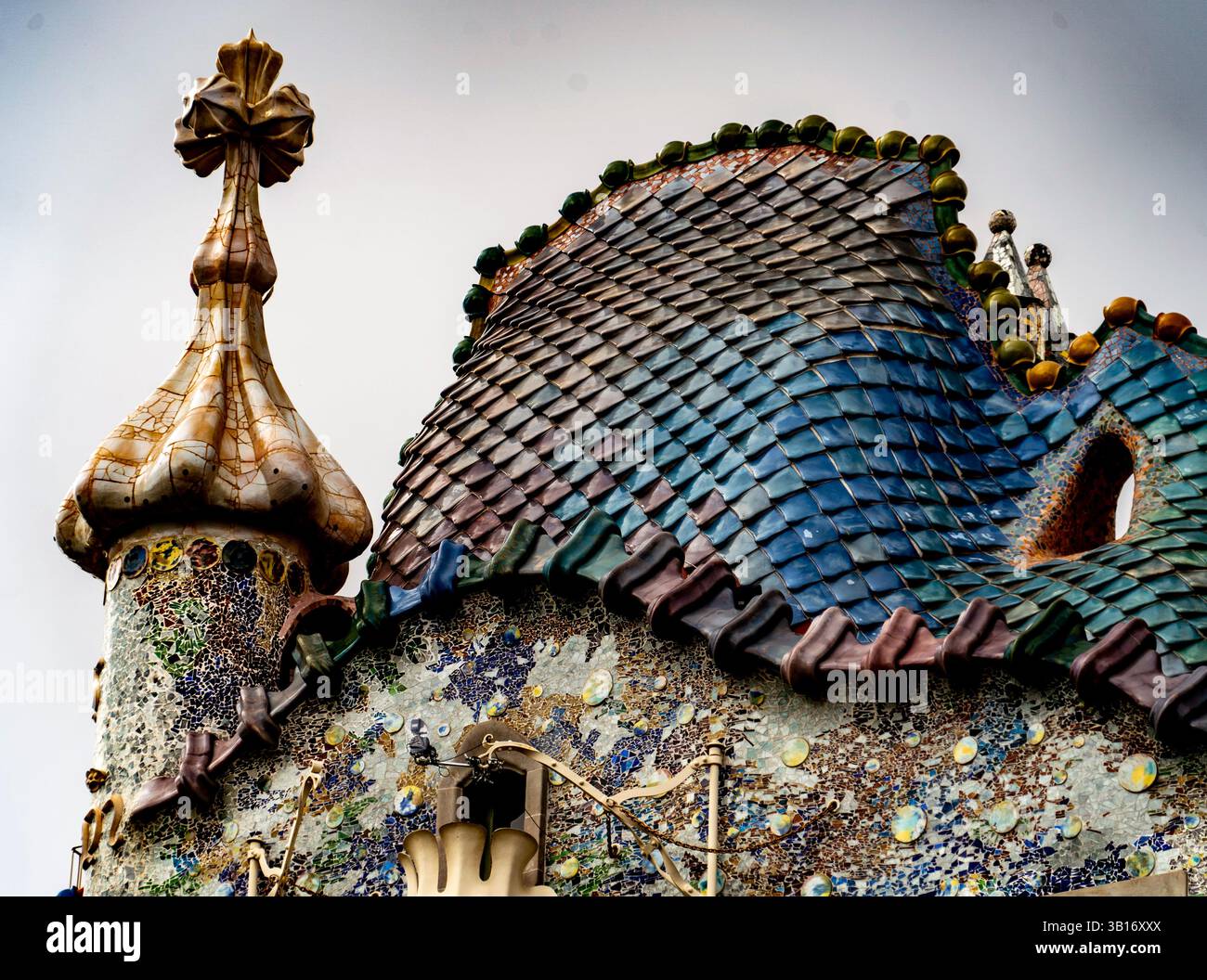 Una vista ravvicinata di una struttura architettonica unica caratterizzata da un tetto colorato e testurizzato con intricate piastrelle e una guglia decorativa. Il design sh Foto Stock