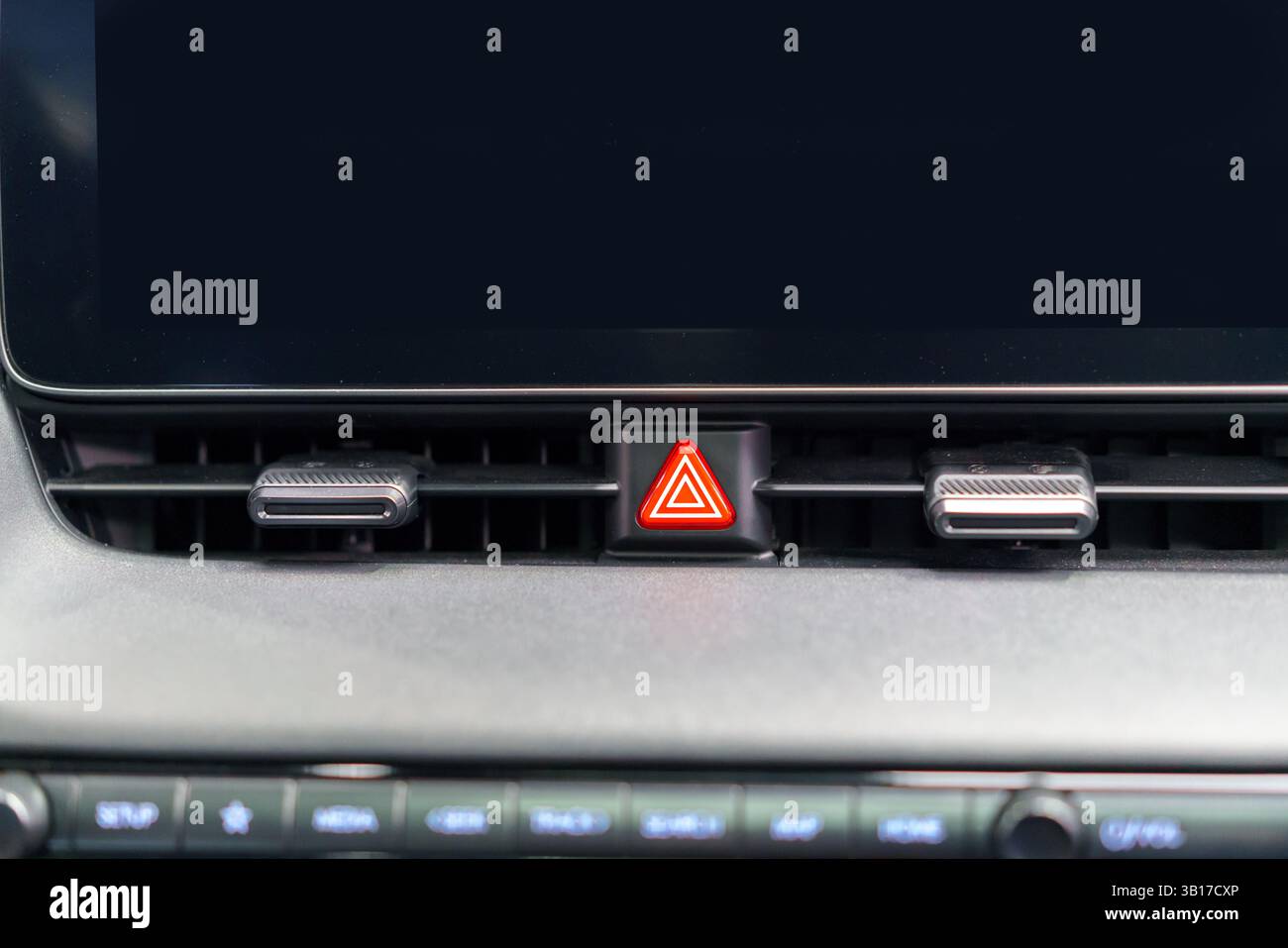 Primo piano di un pulsante delle luci di emergenza sulla bocchetta di ventilazione del cruscotto dell'auto, che enfatizza la sicurezza, il design elegante e il controllo intuitivo in un veicolo moderno. Foto Stock