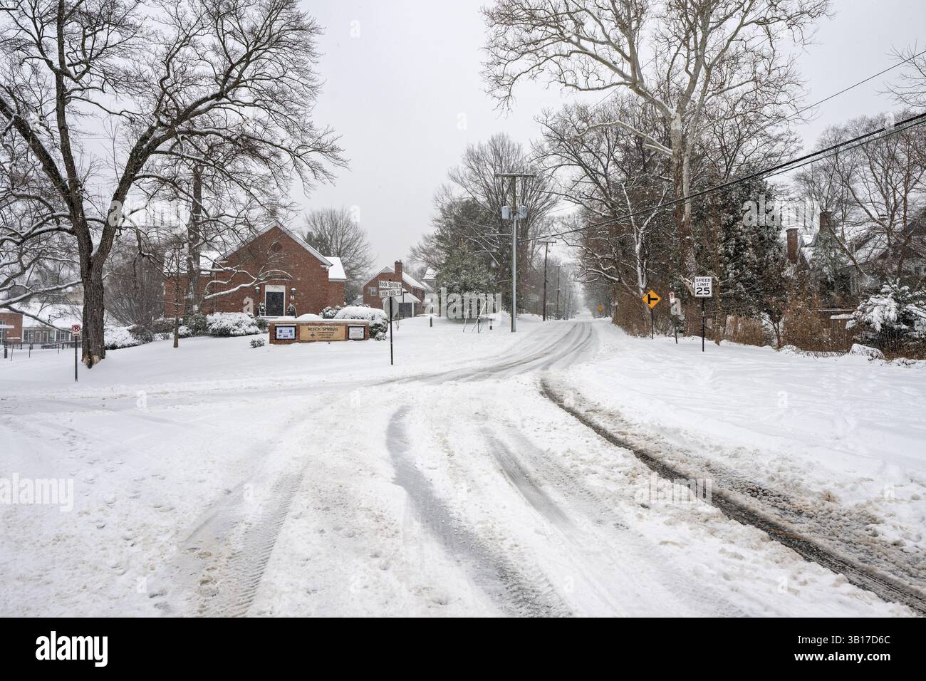 ARLINGTON, Virginia - Un incrocio innevato tra Little Falls Road e Rock Spring Road ad Arlington mostra condizioni non arate a seguito di una tempesta invernale. Le strade residenziali rimangono coperte da un accumulo di neve fresca, creando condizioni di guida pericolose per i residenti locali. Questa scena pre-arata dimostra l'impatto del clima invernale sulle reti di trasporto suburbane della Virginia settentrionale. La contea di Arlington in genere dà la priorità alle arterie principali e alle vie di emergenza prima di sgombrare gli incroci residenziali come questo. Foto Stock