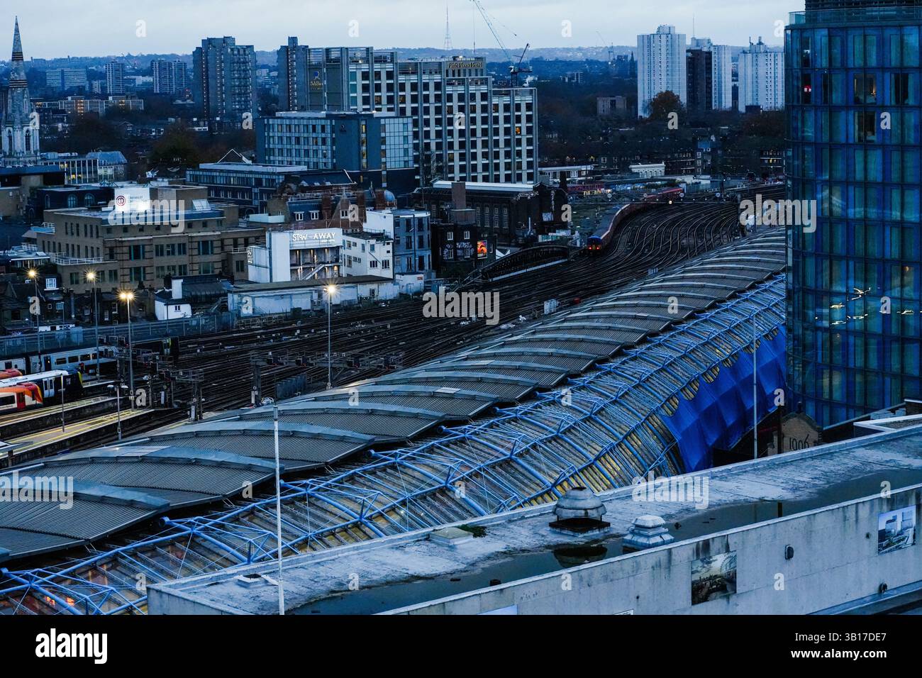 Il crepuscolo si adagia sul paesaggio urbano di Londra, con binari e piattaforme che si intrecciano tra edifici e infrastrutture vicino alla stazione Waterloo Green. Foto Stock
