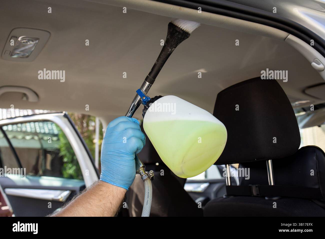 Applicazione di una soluzione speciale per rimuovere le macchie dalla tappezzeria della vettura. Pulire la macchina. Foto Stock