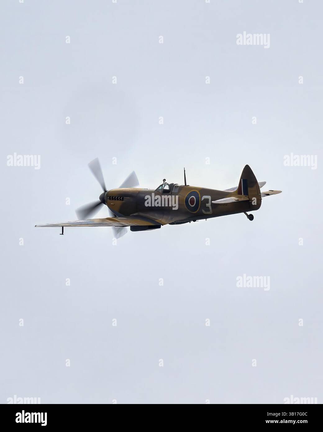 Un aereo da caccia Supermarine Spitfire della RAF dell'era della seconda guerra mondiale vola attraverso un cielo pallido, con elica che gira, a Duxford, in Inghilterra. Foto Stock
