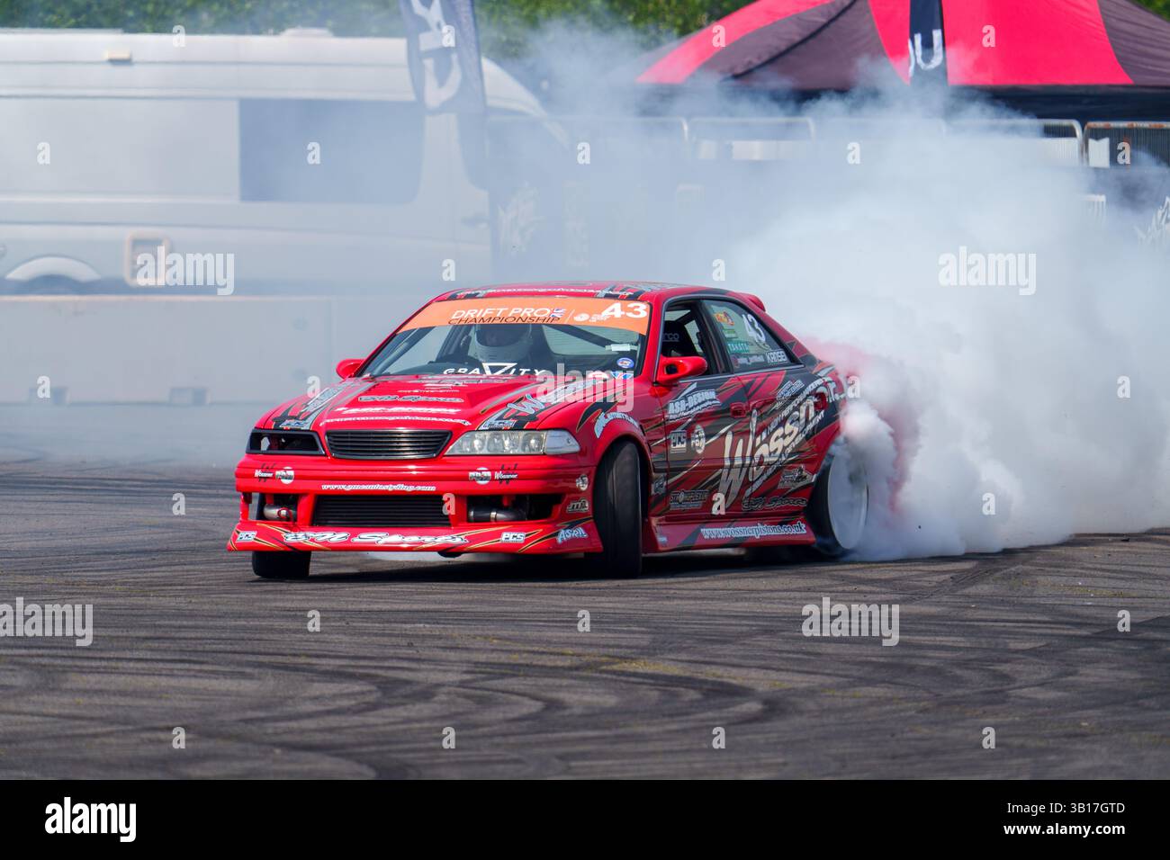 Red modificata Toyota JZX100 drift car numero 43, generando fumo di pneumatici durante una gara di drift a Silverstone, in Inghilterra, davanti alla folla. Foto Stock