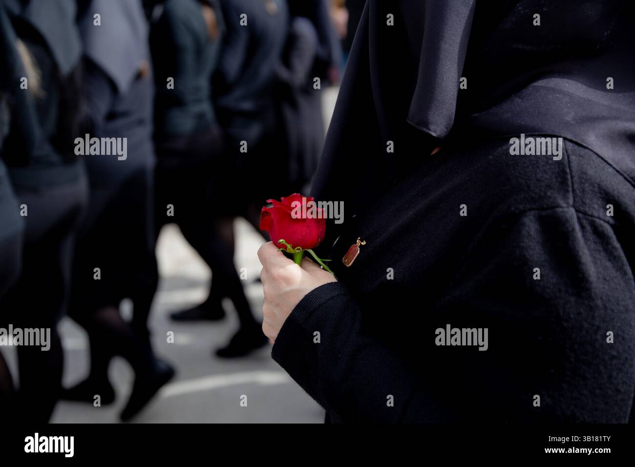 Una rosa rossa accompagna le donne velate del coro della Processione "Desolata", Canosa di Puglia, Provincia di Barletta-Andria-Trani, Italia Foto Stock